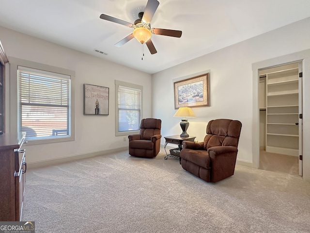 living area with visible vents, plenty of natural light, a ceiling fan, and carpet