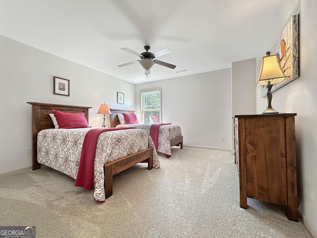 carpeted bedroom with visible vents, baseboards, and a ceiling fan