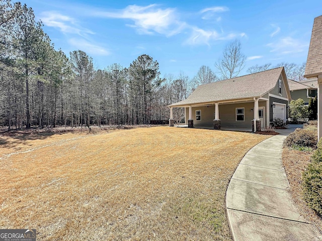 exterior space with a yard, covered porch, driveway, and an attached garage