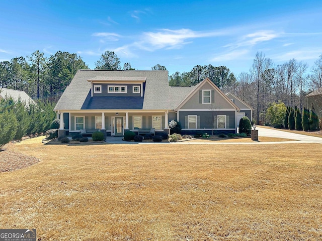 view of front of home with a front lawn, a porch, concrete driveway, and a shingled roof