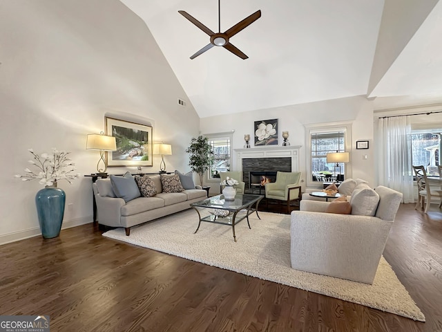 living area featuring a wealth of natural light, a stone fireplace, wood finished floors, and a ceiling fan