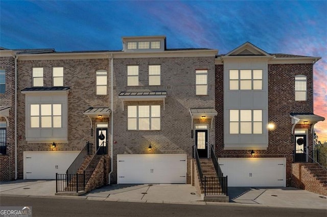 townhome / multi-family property featuring a garage and brick siding