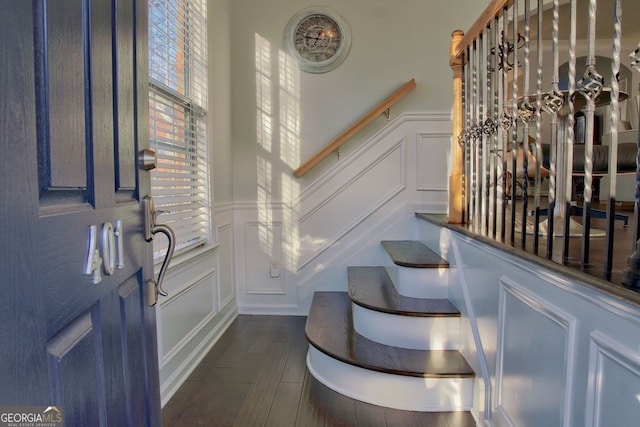 entrance foyer featuring a wainscoted wall, dark wood-style floors, stairs, and a decorative wall
