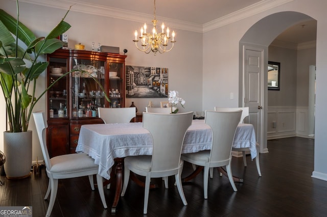 dining room featuring crown molding, wood finished floors, arched walkways, and a chandelier
