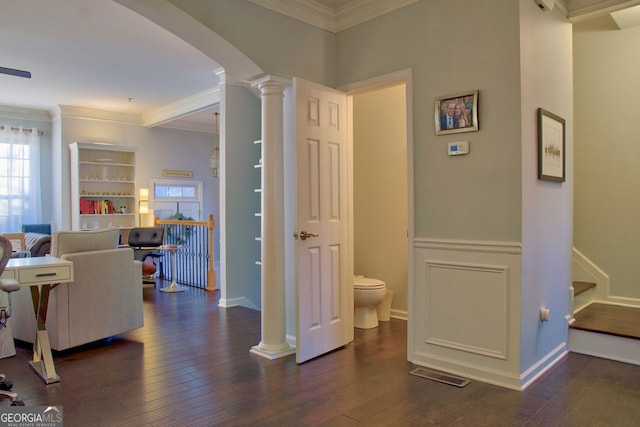 hallway featuring visible vents, decorative columns, dark wood-style flooring, arched walkways, and crown molding