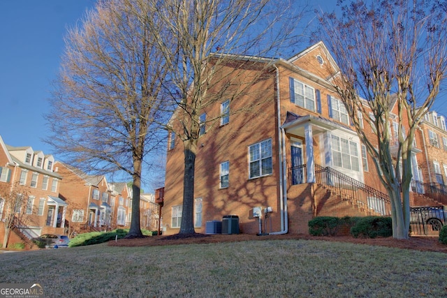 view of side of home featuring a residential view, a lawn, and central AC