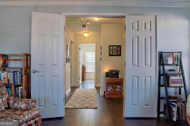 interior space featuring visible vents, baseboards, dark wood finished floors, and crown molding