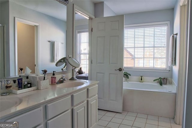 bathroom with tile patterned flooring, a garden tub, double vanity, and a sink