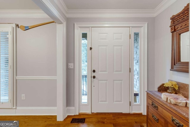 foyer entrance with crown molding, wood finished floors, and visible vents