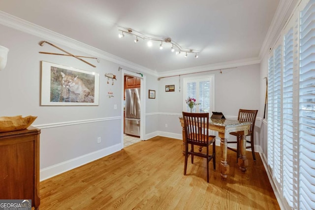 dining space with baseboards, light wood-style floors, and crown molding