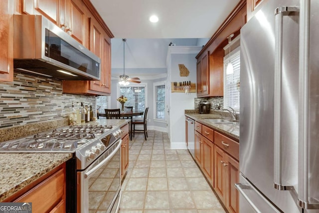 kitchen featuring brown cabinets, appliances with stainless steel finishes, a ceiling fan, and a sink