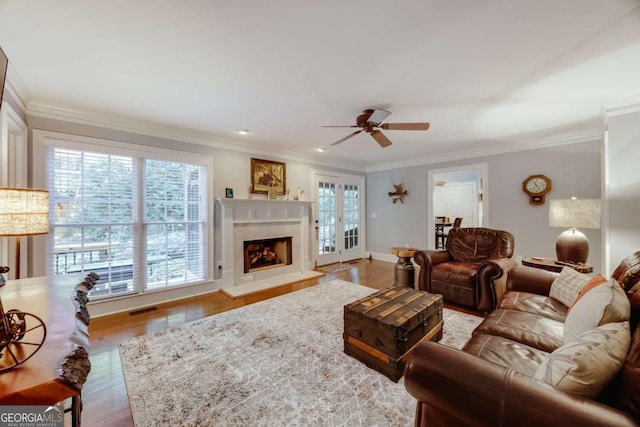 living area featuring visible vents, ornamental molding, wood finished floors, a premium fireplace, and ceiling fan