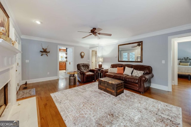 living area featuring light wood-style flooring, baseboards, ceiling fan, and ornamental molding