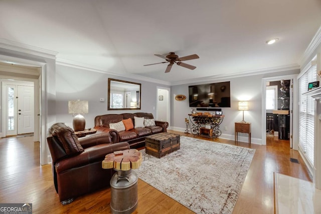 living area with crown molding, wood finished floors, and ceiling fan