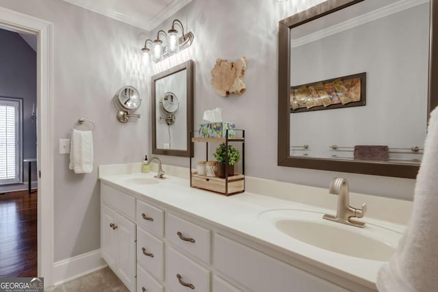 bathroom with crown molding, double vanity, baseboards, and a sink