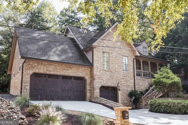 view of front facade with stone siding, concrete driveway, a garage, and a shingled roof