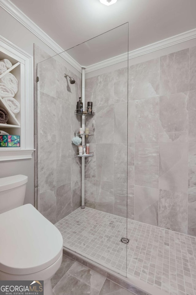 full bathroom featuring a tile shower, toilet, and crown molding