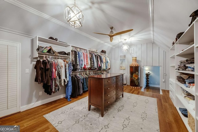 walk in closet with ceiling fan, wood finished floors, and vaulted ceiling