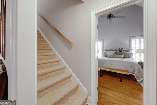 stairway featuring wood finished floors, baseboards, and ceiling fan