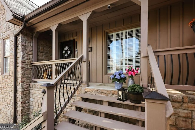 entrance to property with board and batten siding, covered porch, and stone siding