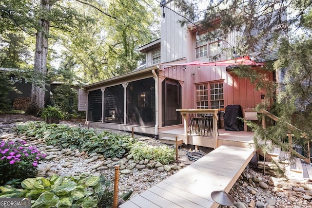 rear view of property with a sunroom and a wooden deck