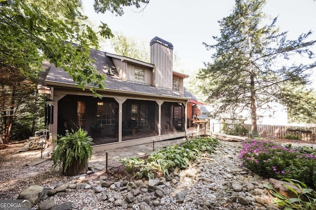 rear view of property with roof with shingles, fence, a sunroom, and a chimney