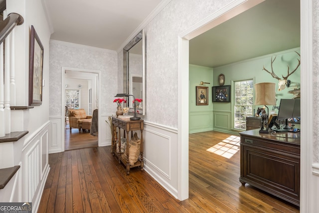 hallway with a decorative wall, wood-type flooring, a wainscoted wall, and ornamental molding
