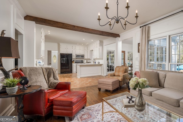 living room with beam ceiling, light wood-style flooring, a notable chandelier, and crown molding
