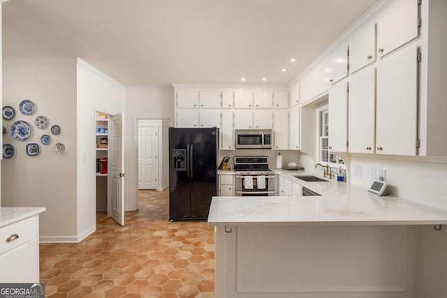 kitchen featuring a peninsula, ornamental molding, a sink, white cabinets, and appliances with stainless steel finishes