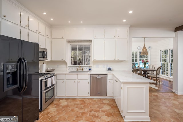 kitchen featuring tasteful backsplash, a peninsula, stainless steel appliances, white cabinetry, and a sink