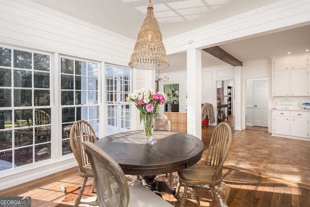 dining space featuring light wood-style flooring, a chandelier, and crown molding
