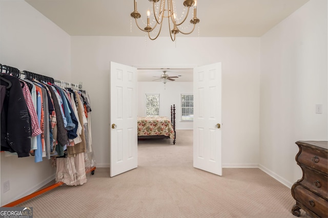 walk in closet with light carpet and a chandelier