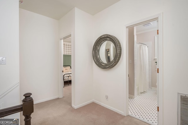 hallway with visible vents, light colored carpet, and baseboards