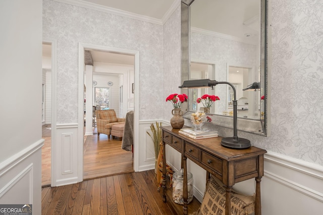 hallway featuring wallpapered walls, a wainscoted wall, and ornamental molding