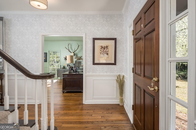 entrance foyer featuring dark wood-type flooring, wallpapered walls, stairway, crown molding, and wainscoting