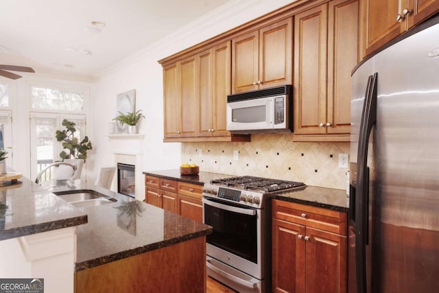 kitchen featuring dark stone countertops, a sink, ornamental molding, stainless steel appliances, and tasteful backsplash