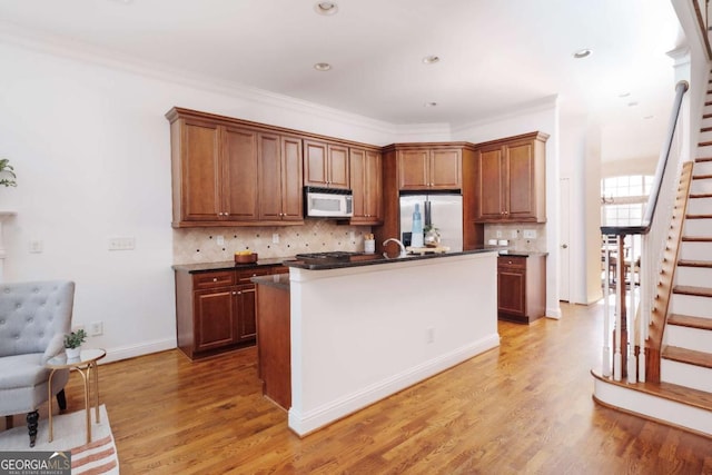 kitchen with dark countertops, light wood-style flooring, white microwave, and stainless steel refrigerator