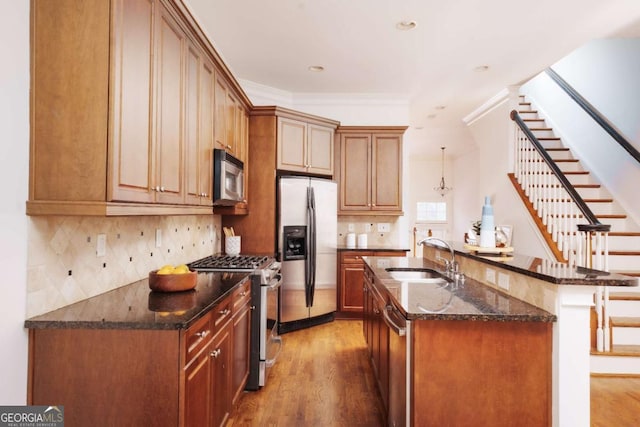 kitchen with wood finished floors, ornamental molding, a sink, appliances with stainless steel finishes, and backsplash