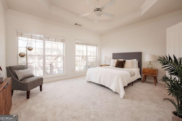 bedroom with a tray ceiling, visible vents, light carpet, and ornamental molding