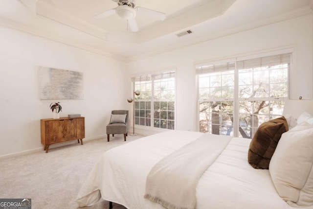 bedroom with carpet, visible vents, baseboards, a tray ceiling, and ceiling fan