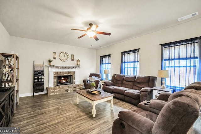 living area featuring visible vents, a ceiling fan, wood finished floors, a fireplace, and baseboards