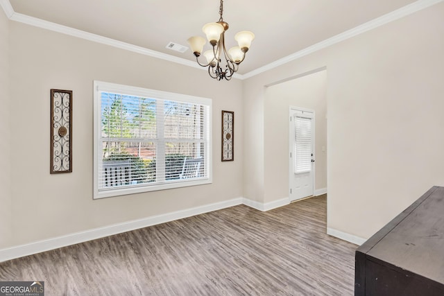 unfurnished dining area with wood finished floors, baseboards, visible vents, crown molding, and a notable chandelier