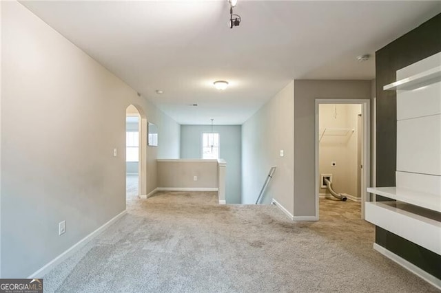 carpeted spare room with baseboards and arched walkways