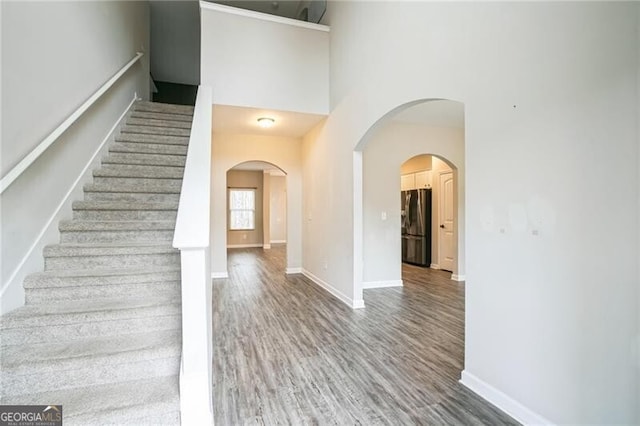 stairway with baseboards, a high ceiling, and wood finished floors