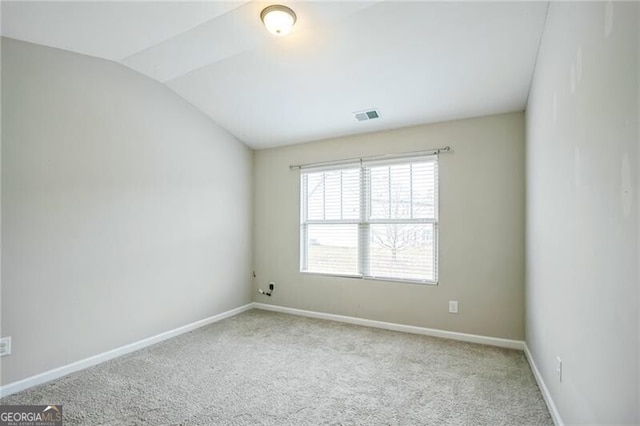 carpeted spare room with lofted ceiling, baseboards, and visible vents