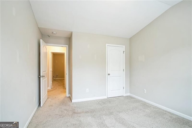 unfurnished bedroom featuring baseboards and light carpet