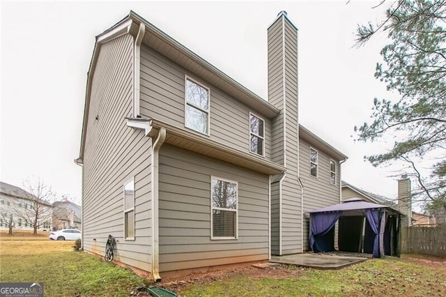 back of property featuring a lawn and a chimney