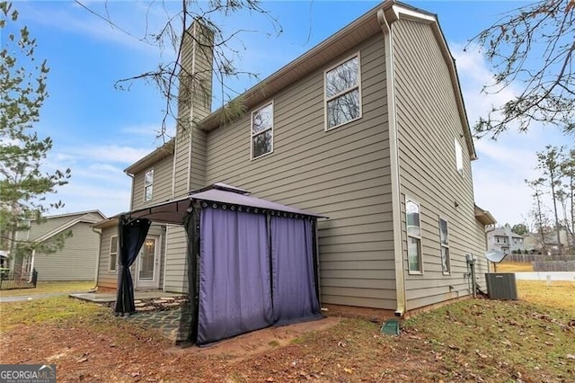 back of house featuring a gazebo and a chimney