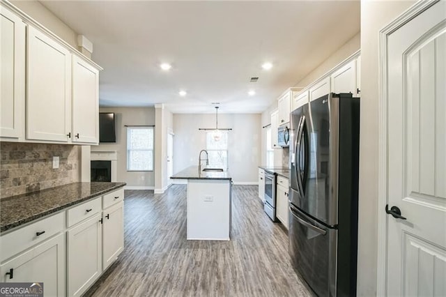 kitchen featuring tasteful backsplash, white cabinetry, stainless steel appliances, and wood finished floors