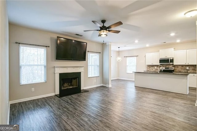 unfurnished living room with ceiling fan, baseboards, dark wood-style floors, and a fireplace